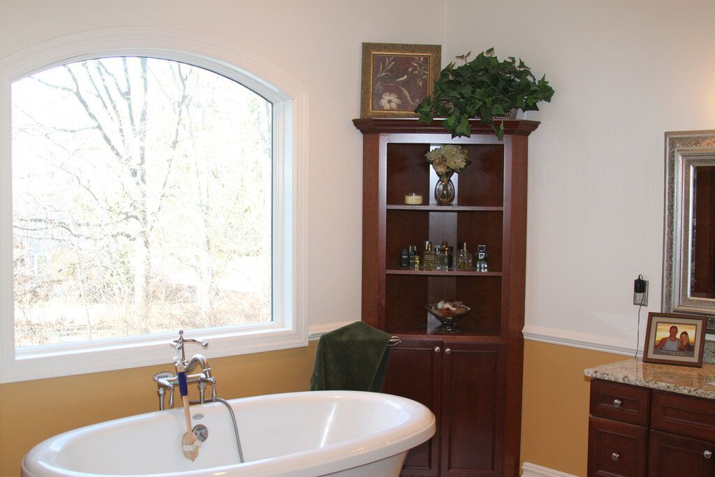 Bathroom with a freestanding tub beneath a large arched window