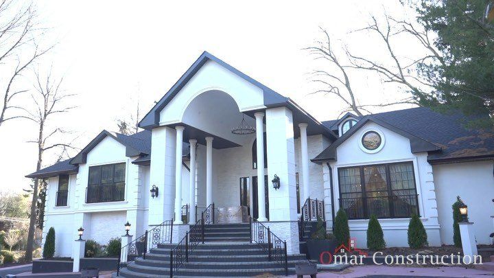 White custom home in Clifton, New Jersey with a columned arched entry and a wide stair up to the front door