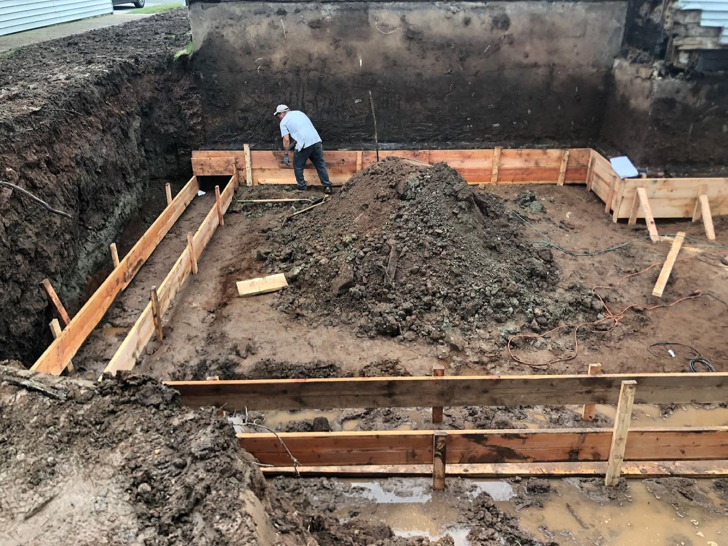 Concrete foundation forms and excavation for a new home in New Jersey, with a worker on site