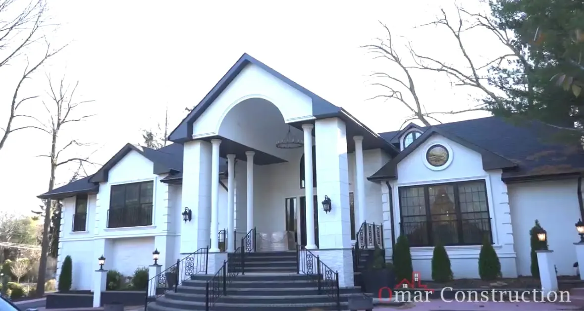 The finished New Jersey home with a white columned entry portico and a new roofline