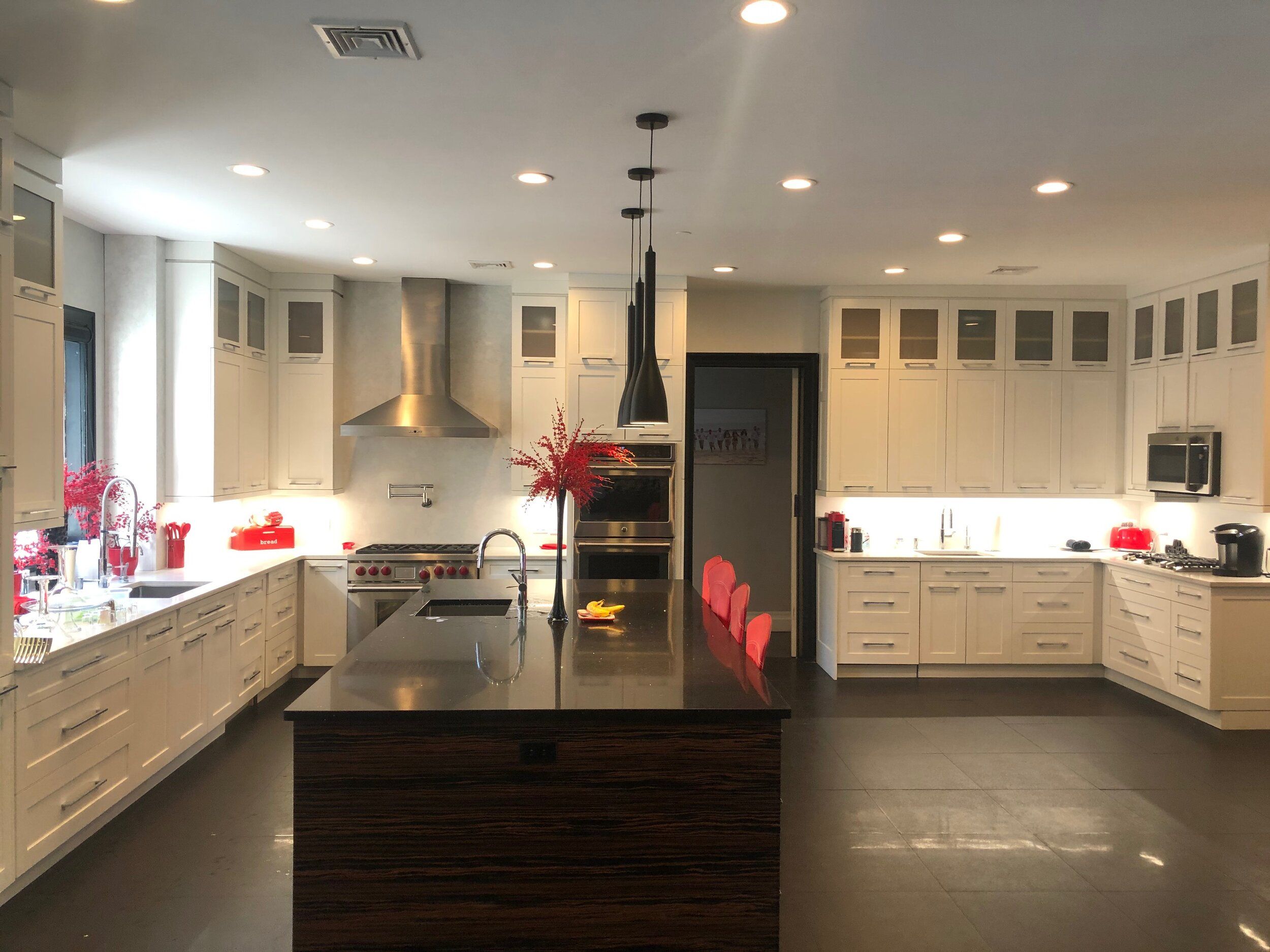 Open kitchen with cream cabinets, a dark island and a stainless range hood
