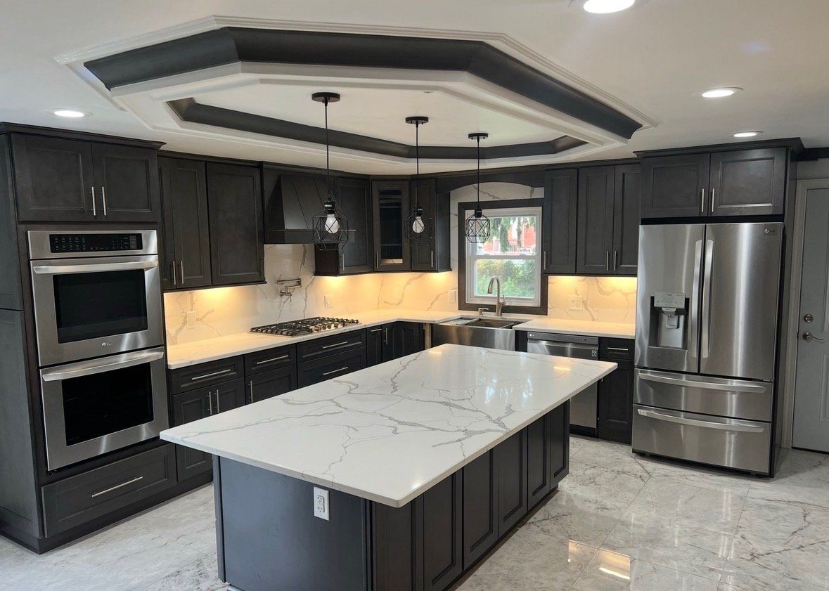 Kitchen with dark cabinets, double wall ovens, stainless appliances and a large white quartz island