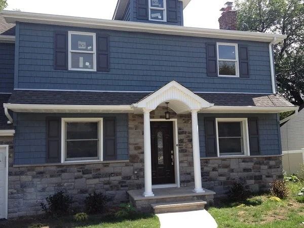New home built by Omar Construction in River Edge, Bergen County, NJ, with blue shingle siding, a stone base and a columned front portico