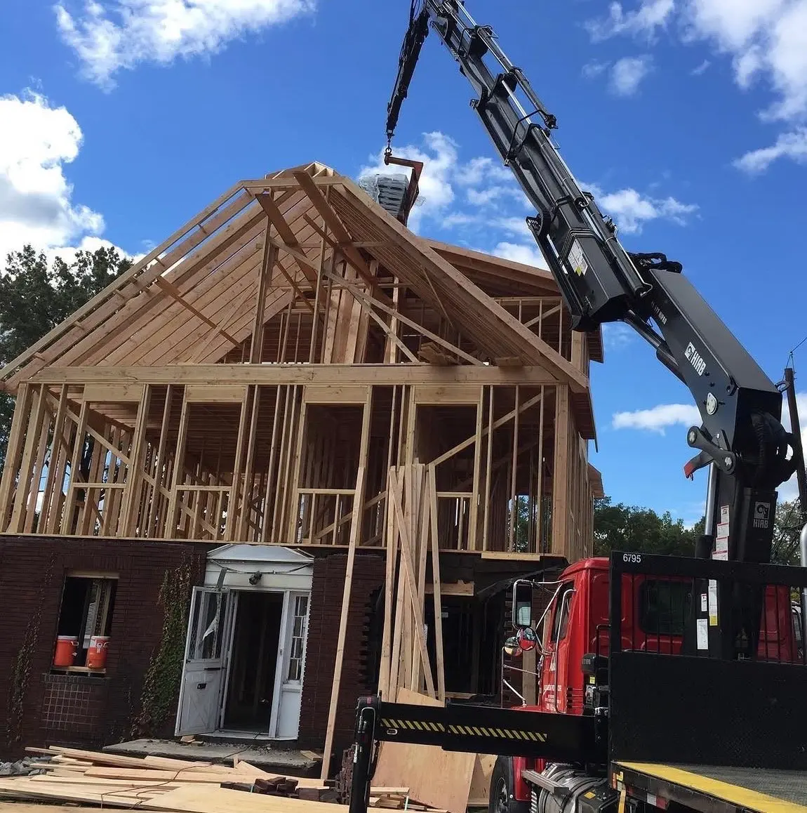 Crane lifting roof framing onto a second-floor addition in Clifton, NJ