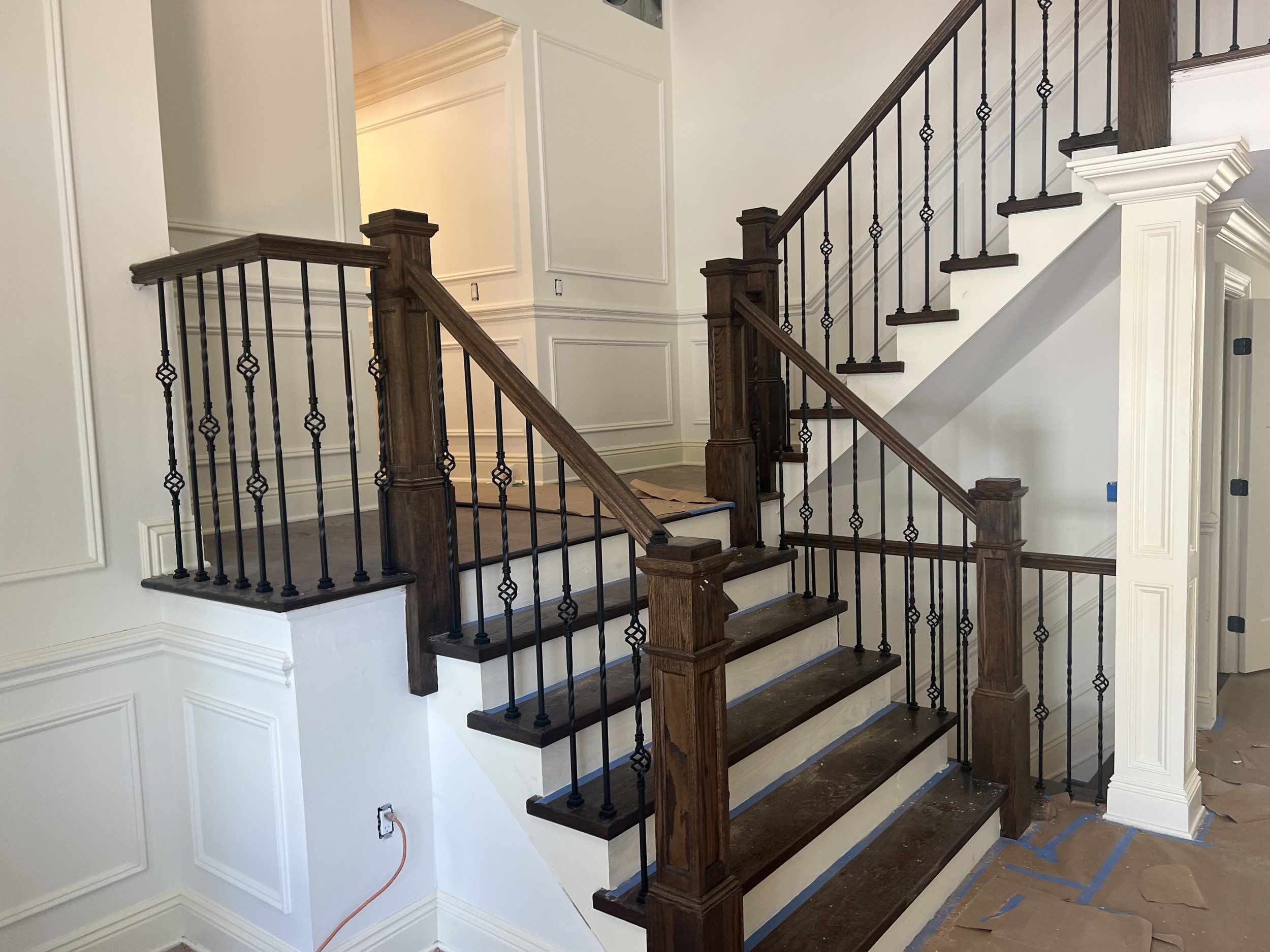 Interior staircase with dark wood treads, iron balusters and white paneled walls