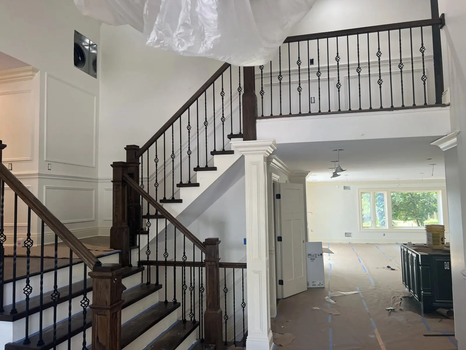 Staircase with dark oak treads, iron balusters and paneled walls during a first- and second-floor renovation in Passaic County, NJ