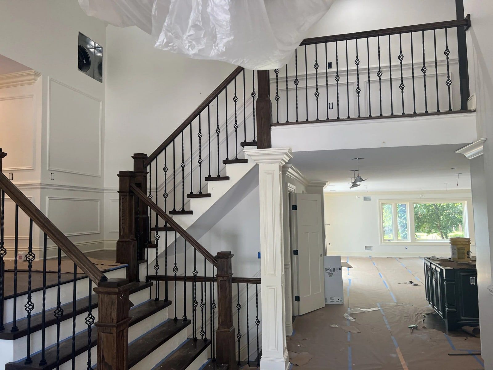 Staircase with dark oak treads, iron balusters and paneled walls during a first- and second-floor renovation in Passaic County, NJ